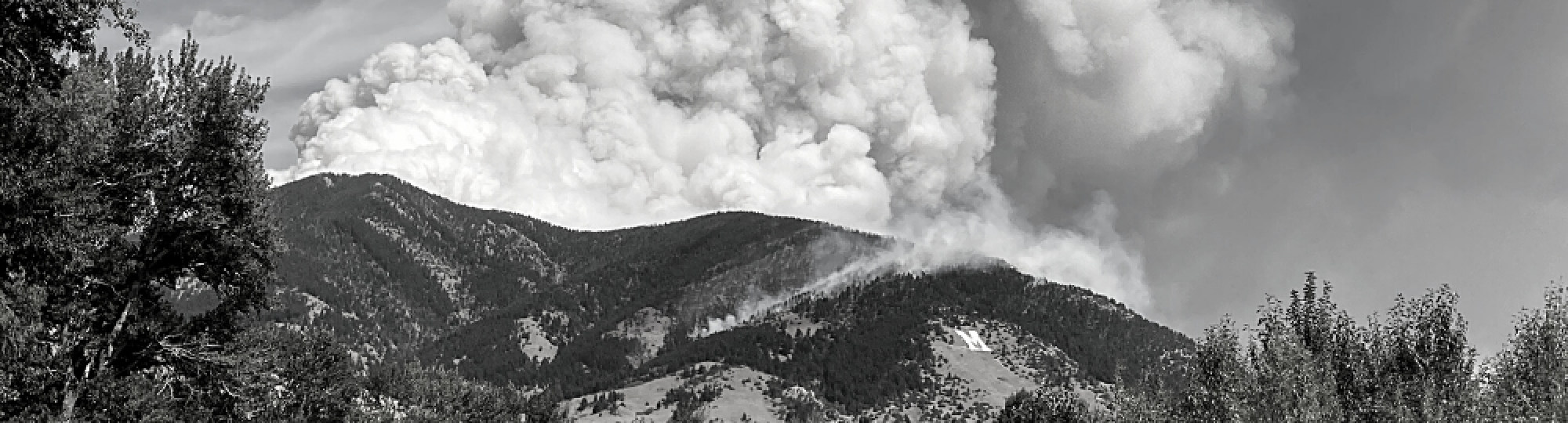 Black and white photo of smoke rising from wildfire in bridger mountains